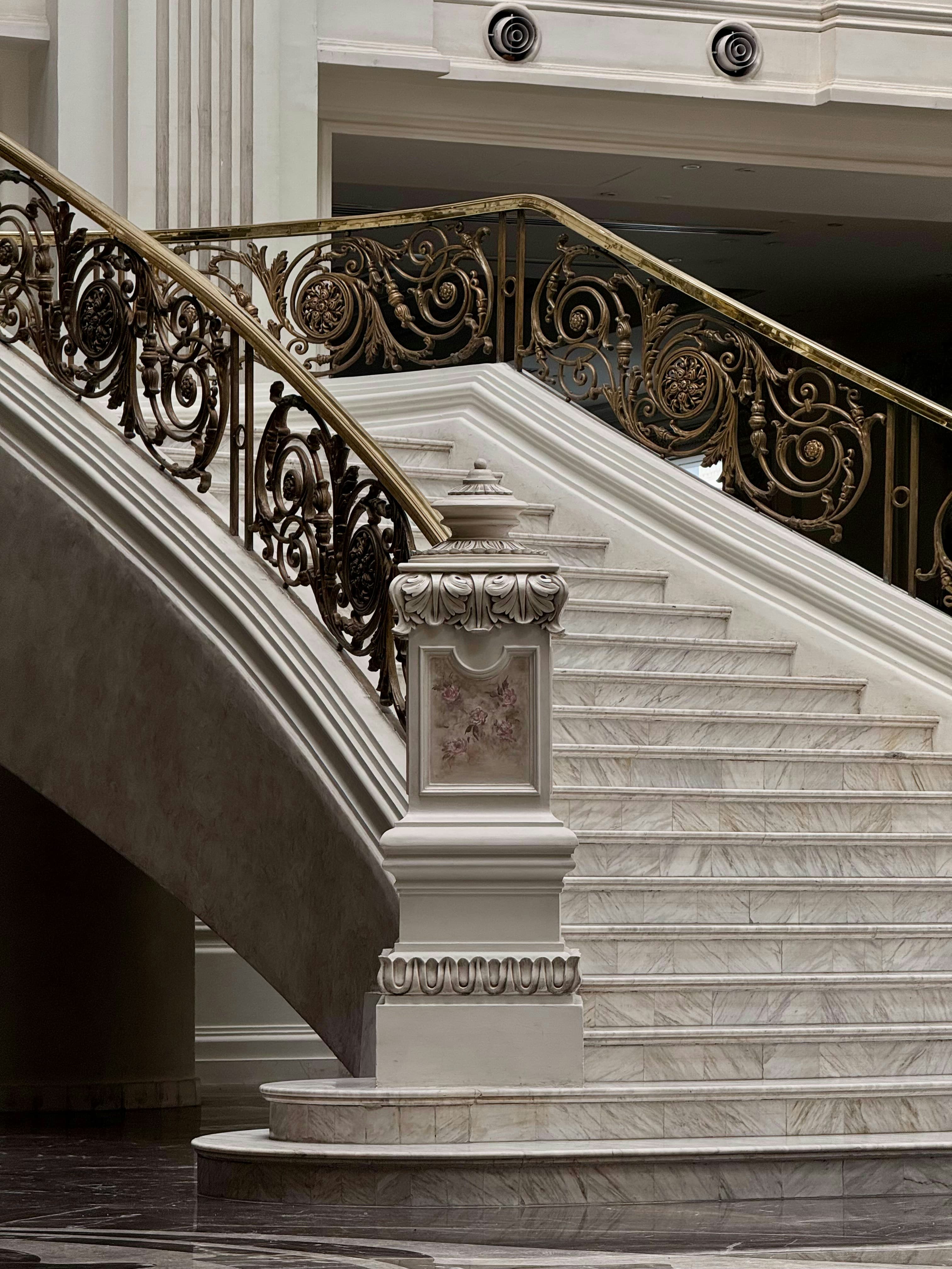 A marble staircase with ornate wrought-iron railings