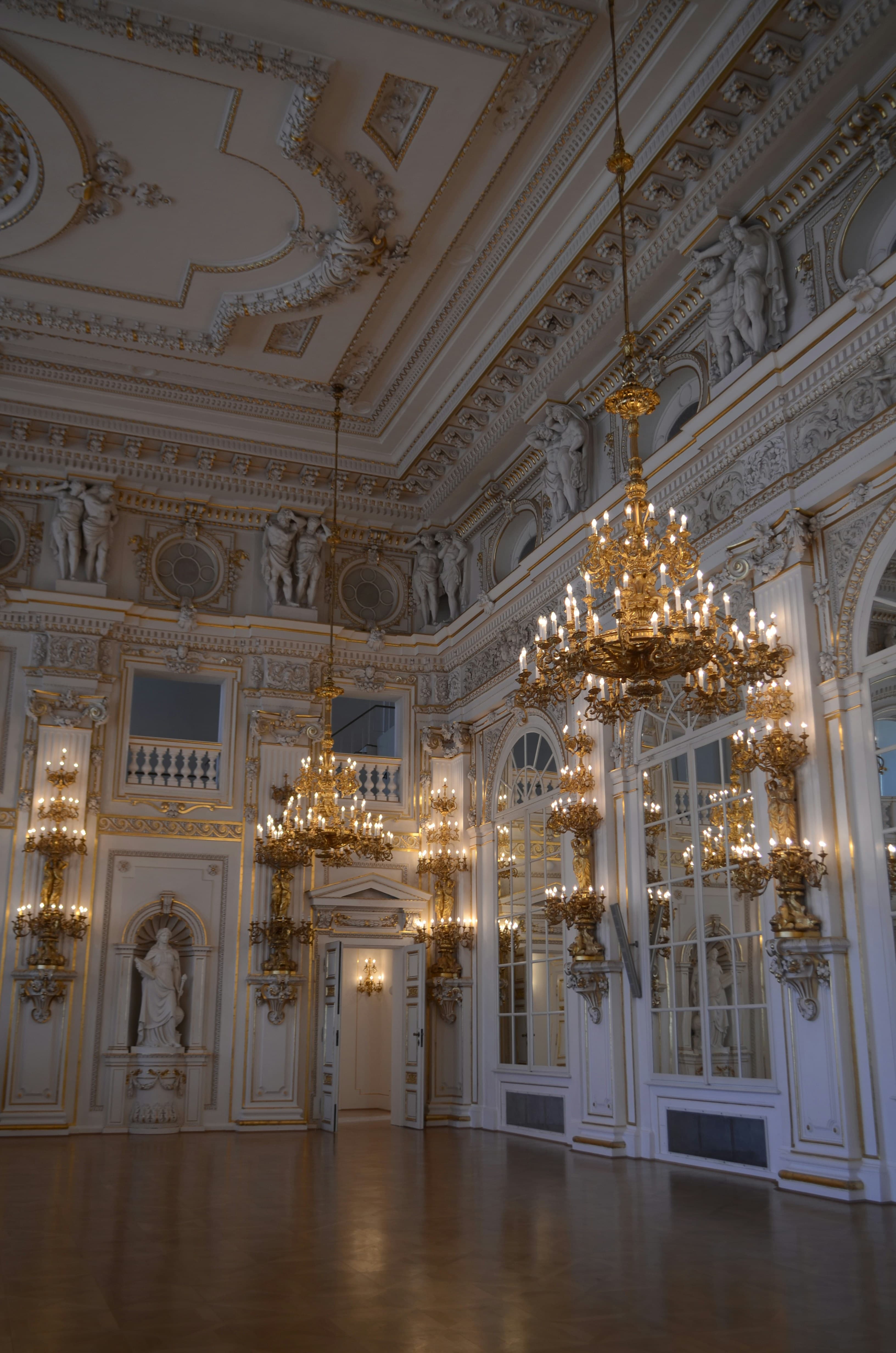 A white and gold ballroom with crystal chandeliers