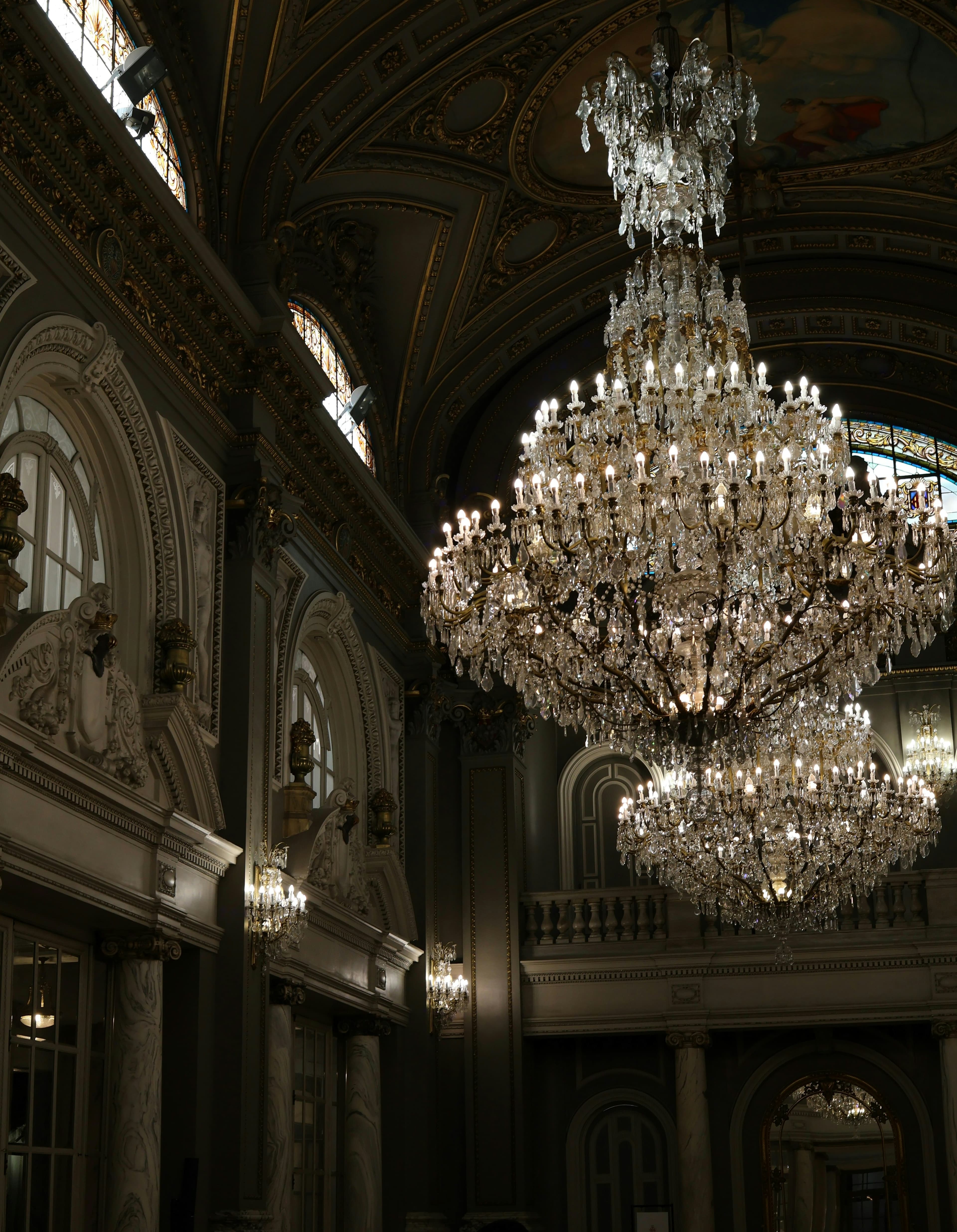 Crystal chandeliers glowing in a dark, ornate hall